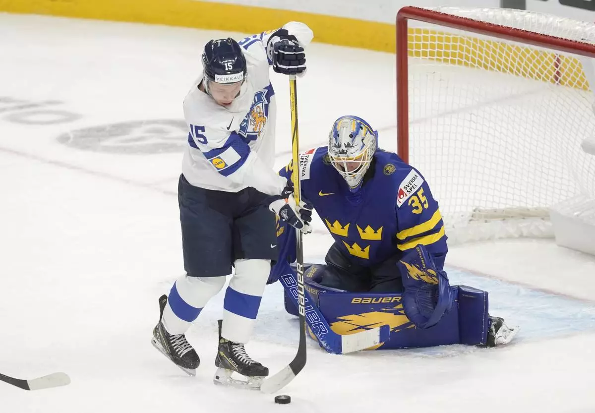 Finland forward Tuomas Uronen (15) tries to tip a shot past Sweden goaltender Melker Thelin (35) during the second period of a semifinal game at the world junior hockey championship, Saturday, Jan. 4, 2025 in Ottawa, Ontario. (Adrian Wyld/The Canadian Press via AP)
