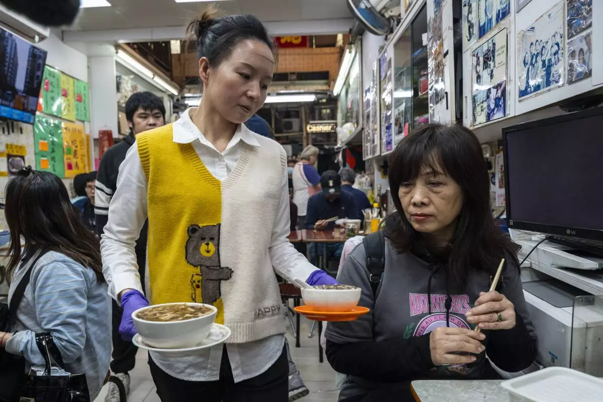 A waitress serves a customer at the family-run snake soup restaurant in Hong Kong, Monday, Jan. 6, 2025. (AP Photo/Chan Long Hei)
