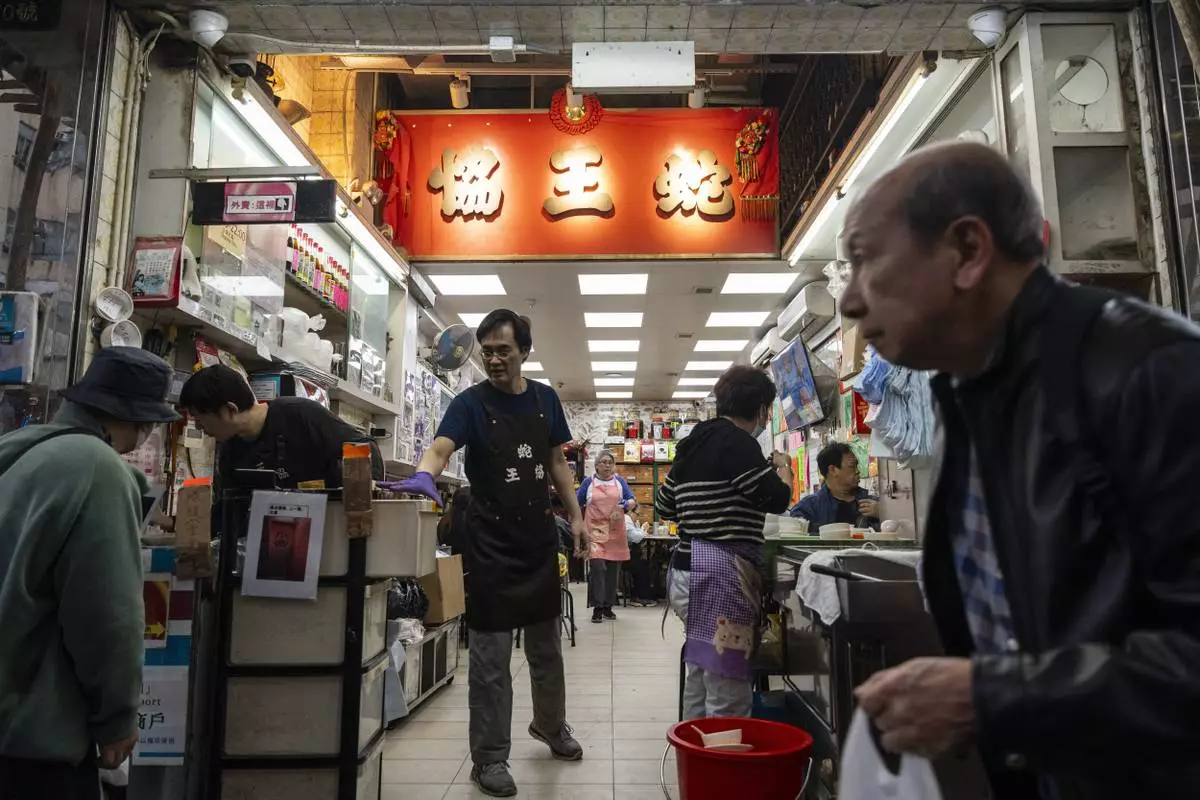 People walk past the family-run snake soup restaurant in Hong Kong, Monday, Jan. 6, 2025. (AP Photo/Chan Long Hei)