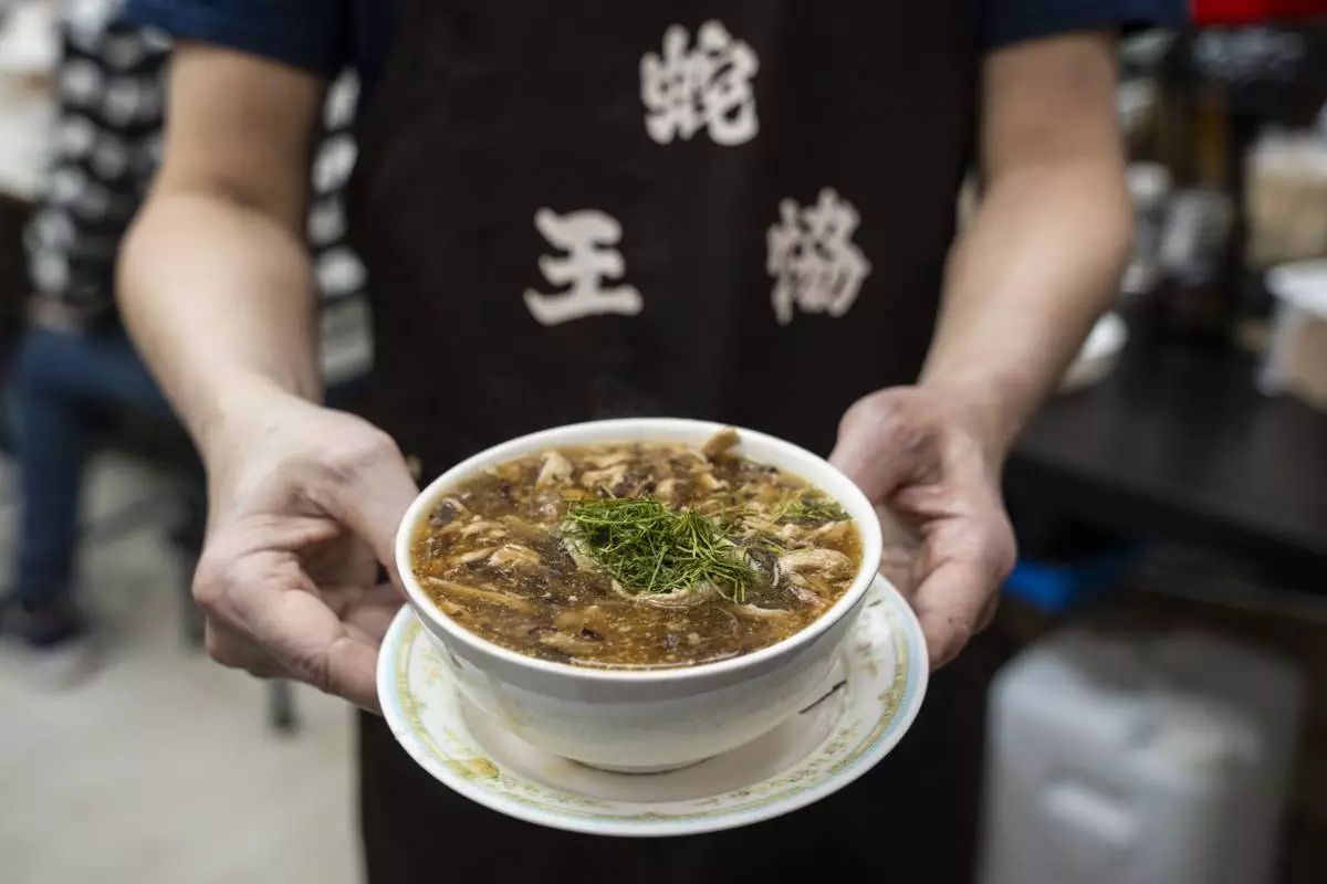 A waiter holds a bowl of snake soup at a restaurant in Hong Kong, Monday, Jan. 6, 2025. (AP Photo/Chan Long Hei)