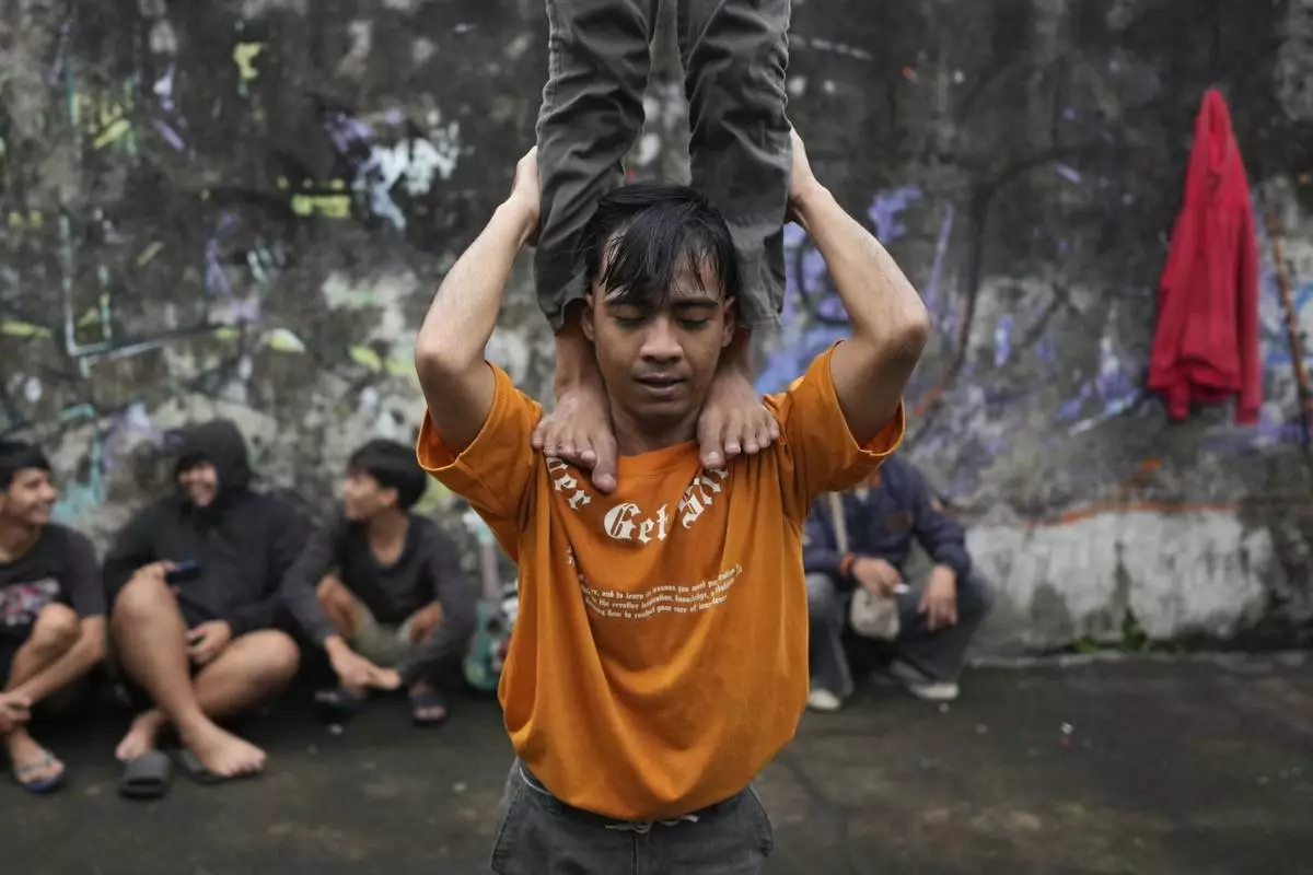 Members of dragon dance club Naga Merah Putih (Red White Dragon) which is named after Indonesian national colors, Mumammad Fadil, top, and Muhammad Ilman, bottom, train ahead of a performance, in Bogor, West Java, Indonesia, Friday, Jan. 24, 2025. (AP Photo/Dita Alangkara)