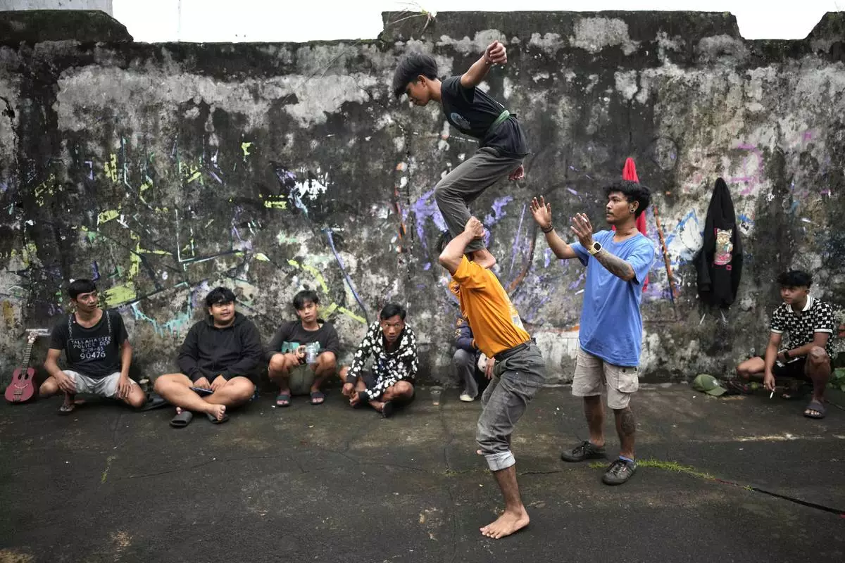 Members of dragon dance club Naga Merah Putih (Red White Dragon), named after Indonesian national colors, Mumammad Fadil, top, and Muhammad Ilman, bottom, practice their dance movements as Aji Permana, right assists, in Bogor, West Java, Indonesia, Friday, Jan. 24, 2025. (AP Photo/Dita Alangkara)