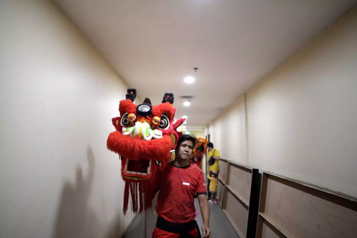 A member of dragon dance club Naga Merah Putih (Red White Dragon), named after Indonesian national colors, carry a dragon puppet as he and his team leave the changing room to perform in a Lunar New Year celebration, at a shopping mall in Bogor, West Java, Indonesia, Sunday, Jan. 26, 2025. (AP Photo/Dita Alangkara)
