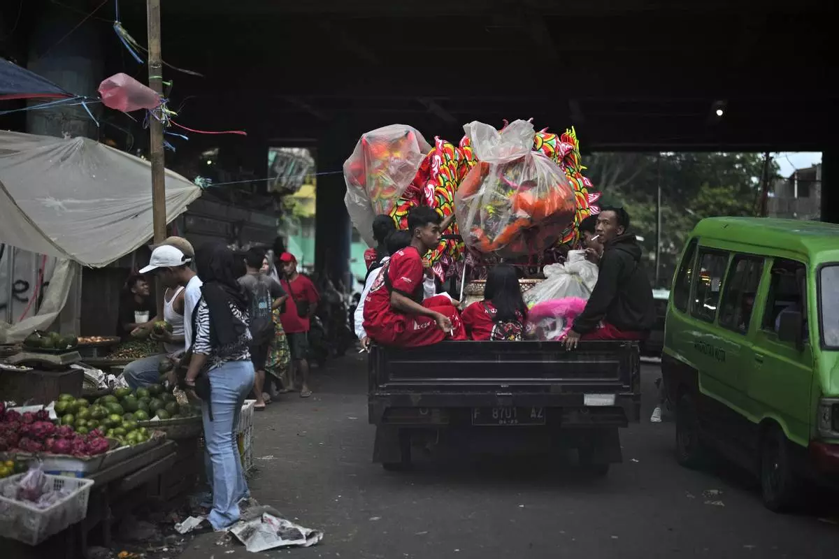 Members of dragon dance club Naga Merah Putih (Red White Dragon) sit on the back of a truck as they leave for a shopping mall to perform in a Lunar New Year celebration, in Bogor, West Java, Indonesia, Sunday, Jan. 26, 2025. (AP Photo/Dita Alangkara)