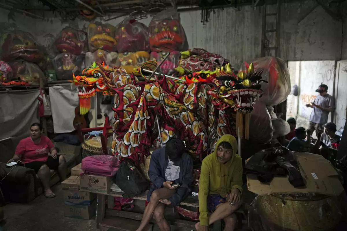 Members of dragon dance club Naga Merah Putih (Red White Dragon) which is named after Indonesian national colors, sit near dragon and lion puppets at the in Bogor, West Java, Indonesia, Thursday, Jan. 23, 2025. (AP Photo/Dita Alangkara)