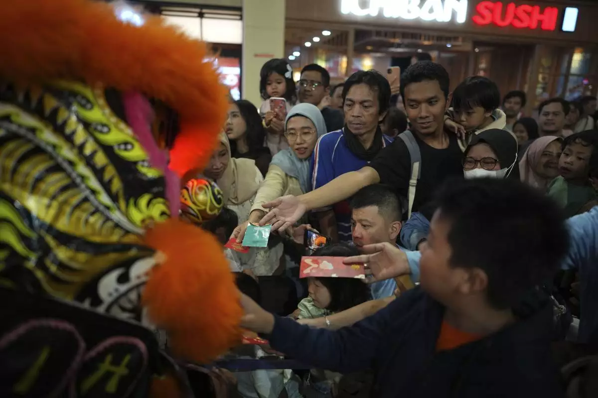 People give "angpau," an envelope containing money traditionally given during Chinese holidays or for special occasions, to members of dragon dance club Naga Merah Putih (Red White Dragon) after a performance at a shopping mall in Bogor, West Java, Indonesia, Sunday, Jan. 26, 2025. (AP Photo/Dita Alangkara)