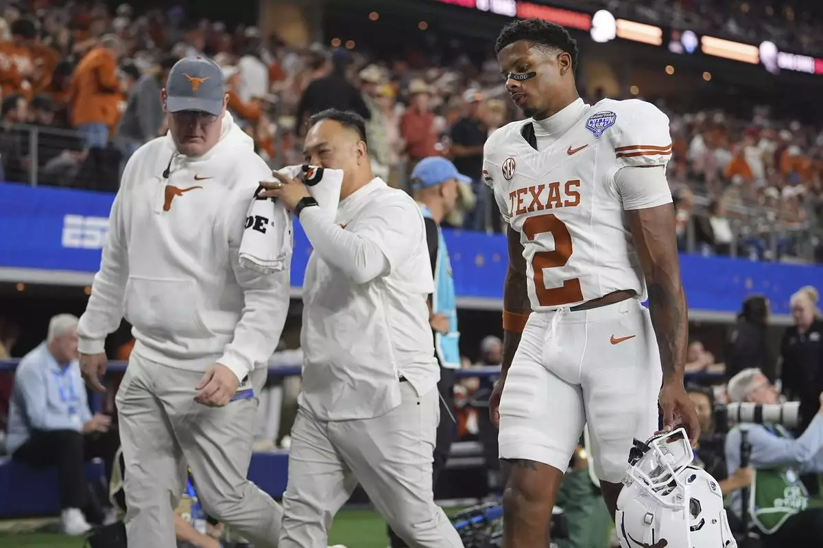 Texas wide receiver Matthew Golden (2) walks off the field with trainers during the first half of the Cotton Bowl College Football Playoff semifinal game against Ohio State, Friday, Jan. 10, 2025, in Arlington, Texas. (AP Photo/Julio Cortez)