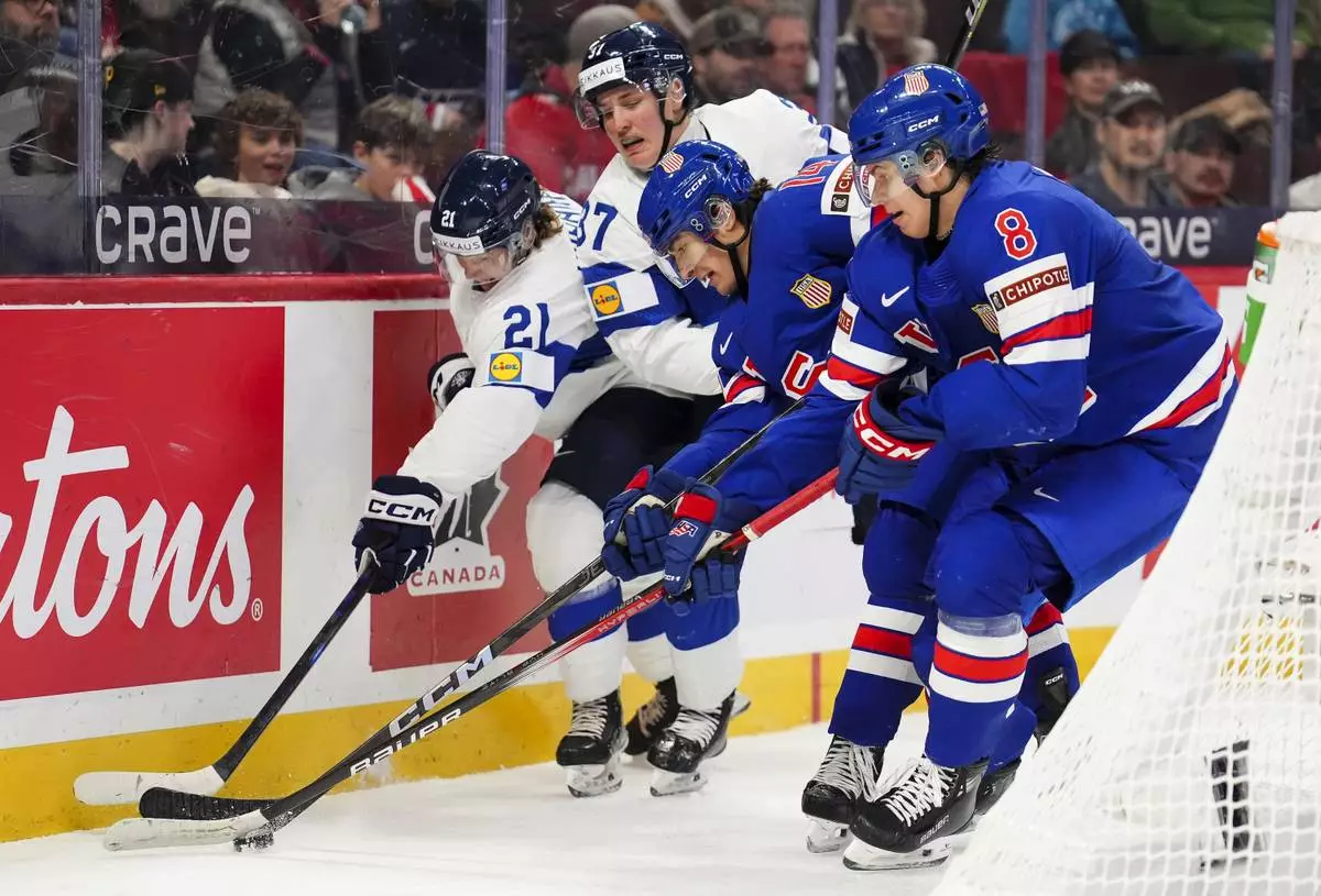 Finland forwards Topias Hynninen (21) and Benjamin Rautiainen (37) fight United States defenseman Aram Minnetian (14) and forward Brandon Svoboda (8) for the puck during second-period IIHF World Junior Hockey Championship gold medal game action in Ottawa, Ontario, Sunday, Jan. 5, 2025. (Sean Kilpatrick/The Canadian Press via AP)