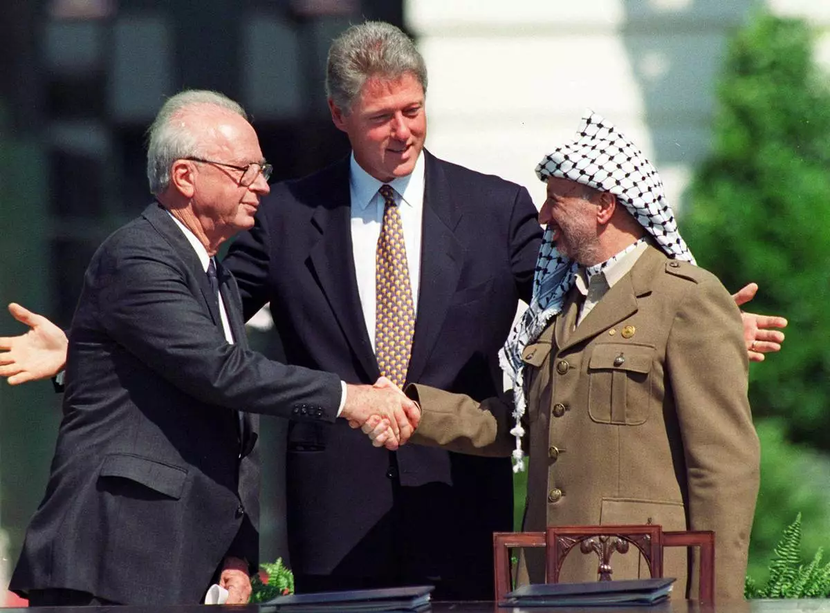 FILE - U.S. President Bill Clinton watches as Israeli Prime Minister Yitzhak Rabin, left, and Palestinian leader Yasser Arafat shake hands, marking the signing of the peace accord between Israel and the Palestinians, in Washington on Sept. 13, 1993. (AP Photo/Ron Edmonds, File)