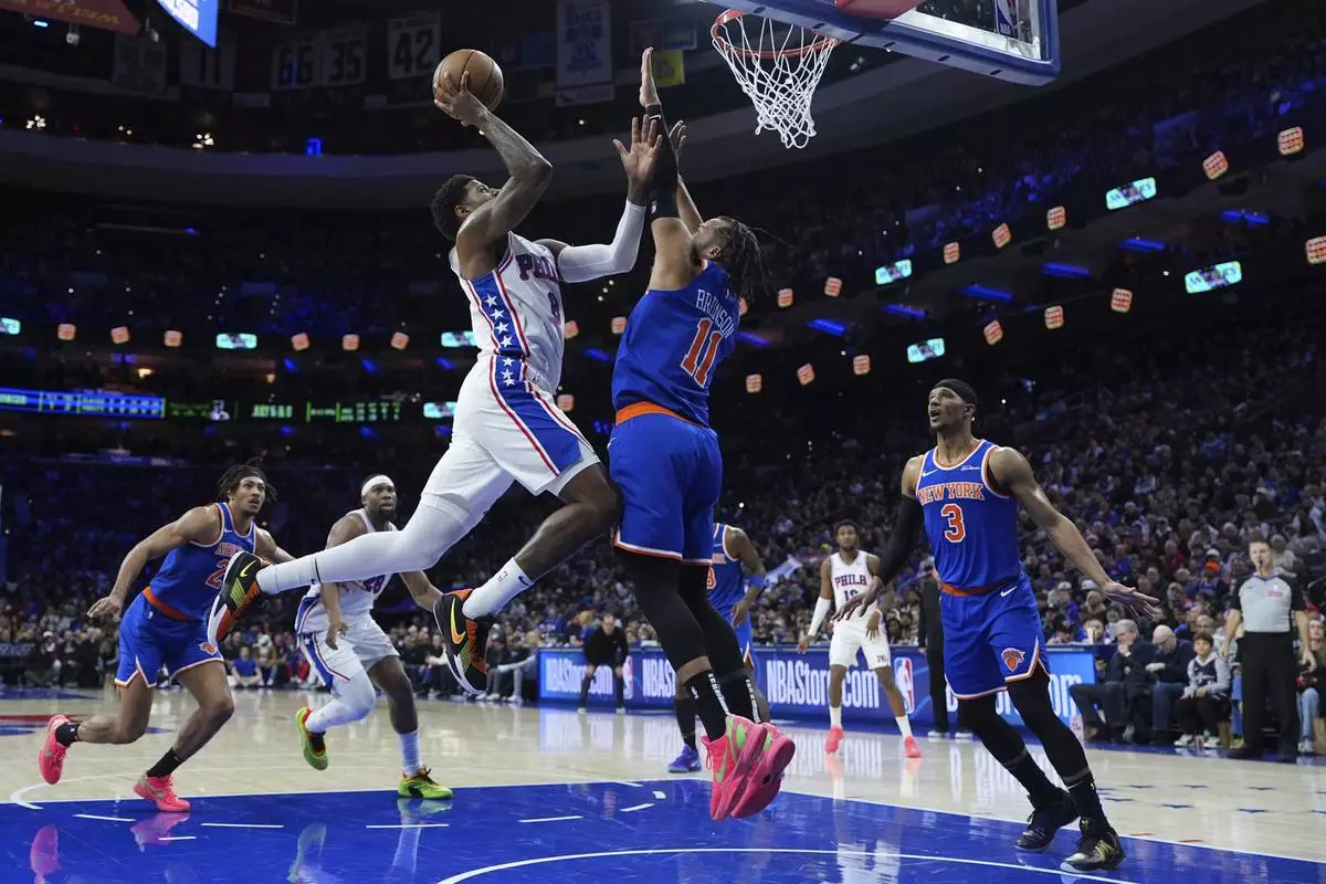 Philadelphia 76ers' Paul George, left, goes up for a shot against New York Knicks' Jalen Brunson during the second half of an NBA basketball game, Wednesday, Jan. 15, 2025, in Philadelphia. (AP Photo/Matt Slocum)