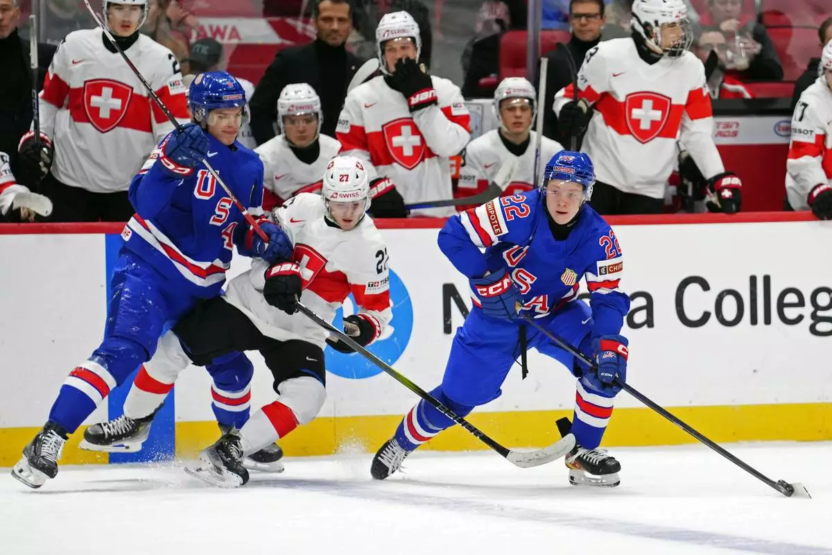USA forward Brandon Svoboda, left, checks Switzerland forward Simon Meier (27) as USA forward Max Plante (22) skates with the puck during the third period of a quarterfinal match at the IIHF World Junior Hockey Championship in Ottawa, Ontario Thursday, Jan. 2, 2025. (Sean Kilpatrick/The Canadian Press via AP)