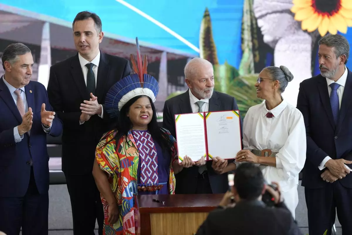 FILE - Brazil's President Luiz Inacio Lula da Silva holds a pact for ecological transformation alongside Minister of the Environment Marina Silva, second from right, and Minister of Indigenous Peoples Sonia Guajajara, to his left, during the agreement's signing at the Planalto presidential palace, in Brasilia, Brazil, Aug. 21, 2024. (AP Photo/Eraldo Peres, File)