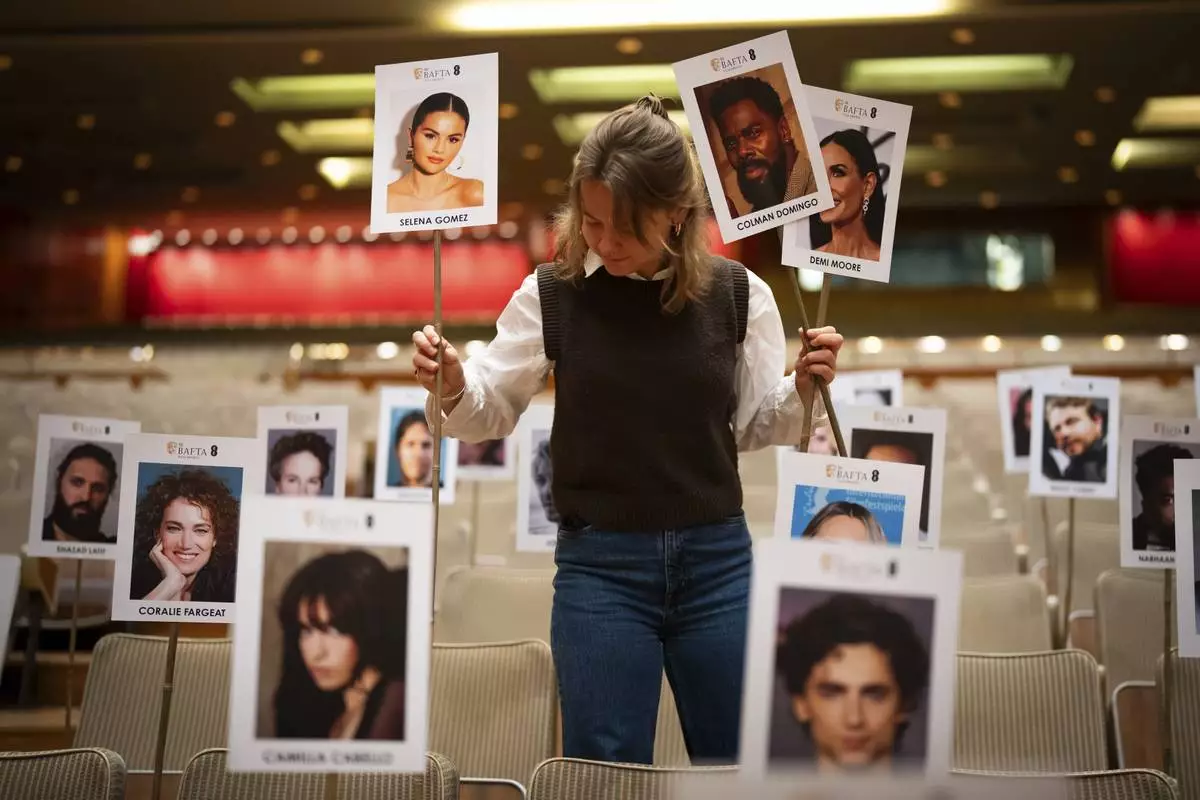 Publicist Abbie Gainher places placards with the images of actors on seats ahead of the BAFTA film awards in London, Wednesday, Feb. 12, 2024. (Photo by Scott A Garfitt/Invision/AP)