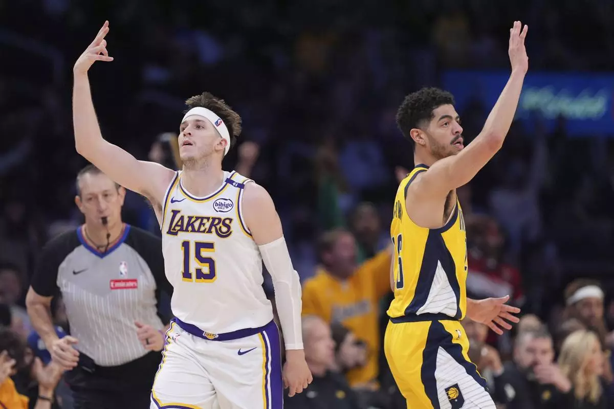 Los Angeles Lakers guard Austin Reaves, left, gestures after hitting a thee-point shot as Indiana Pacers guard Ben Sheppard stands by during the second half of an NBA basketball game Saturday, Feb. 8, 2025, in Los Angeles. (AP Photo/Mark J. Terrill)