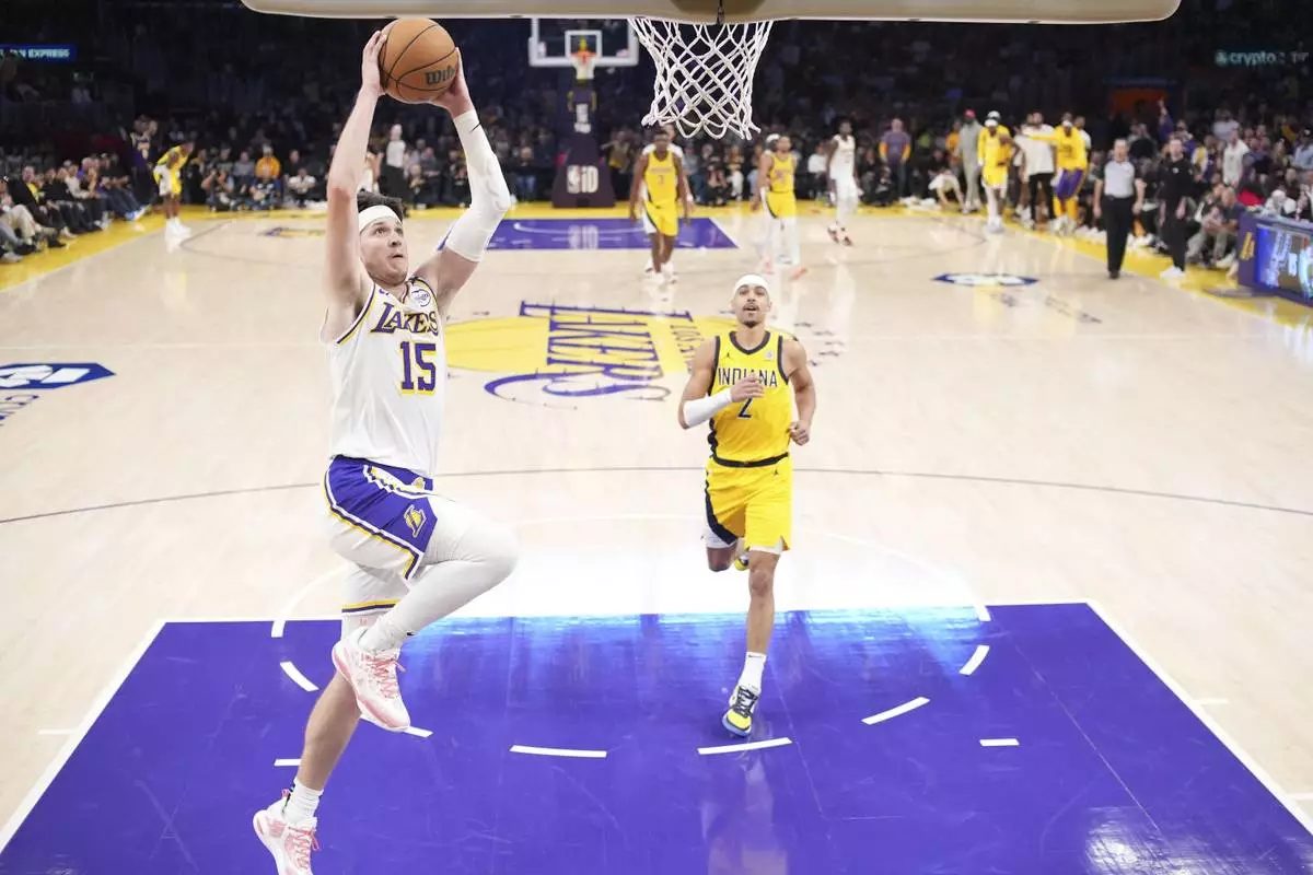 Los Angeles Lakers guard Austin Reaves, left, dunks as Indiana Pacers guard Andrew Nembhard watches during the second half of an NBA basketball game Saturday, Feb. 8, 2025, in Los Angeles. (AP Photo/Mark J. Terrill)