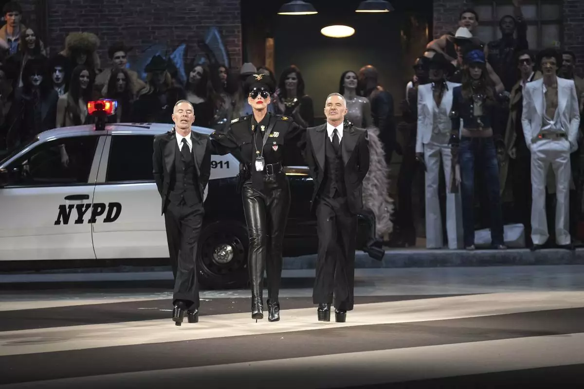 Denmark's actress Brigitte Nielsen, centre, walks with designers Dean Caten, left, and Dan Caten during the Dsquared2 Fall/Winter 2025-2026 men's and women's collection presented in Milan, Italy, Tuesday, Feb. 25, 2025. (AP Photo/Antonio Calanni)