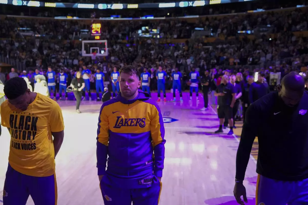 Los Angeles Lakers guard Luka Doncic, center, listens to the national anthem before an NBA basketball game against the Dallas Mavericks, Tuesday, Feb. 25, 2025, in Los Angeles. (AP Photo/Mark J. Terrill)