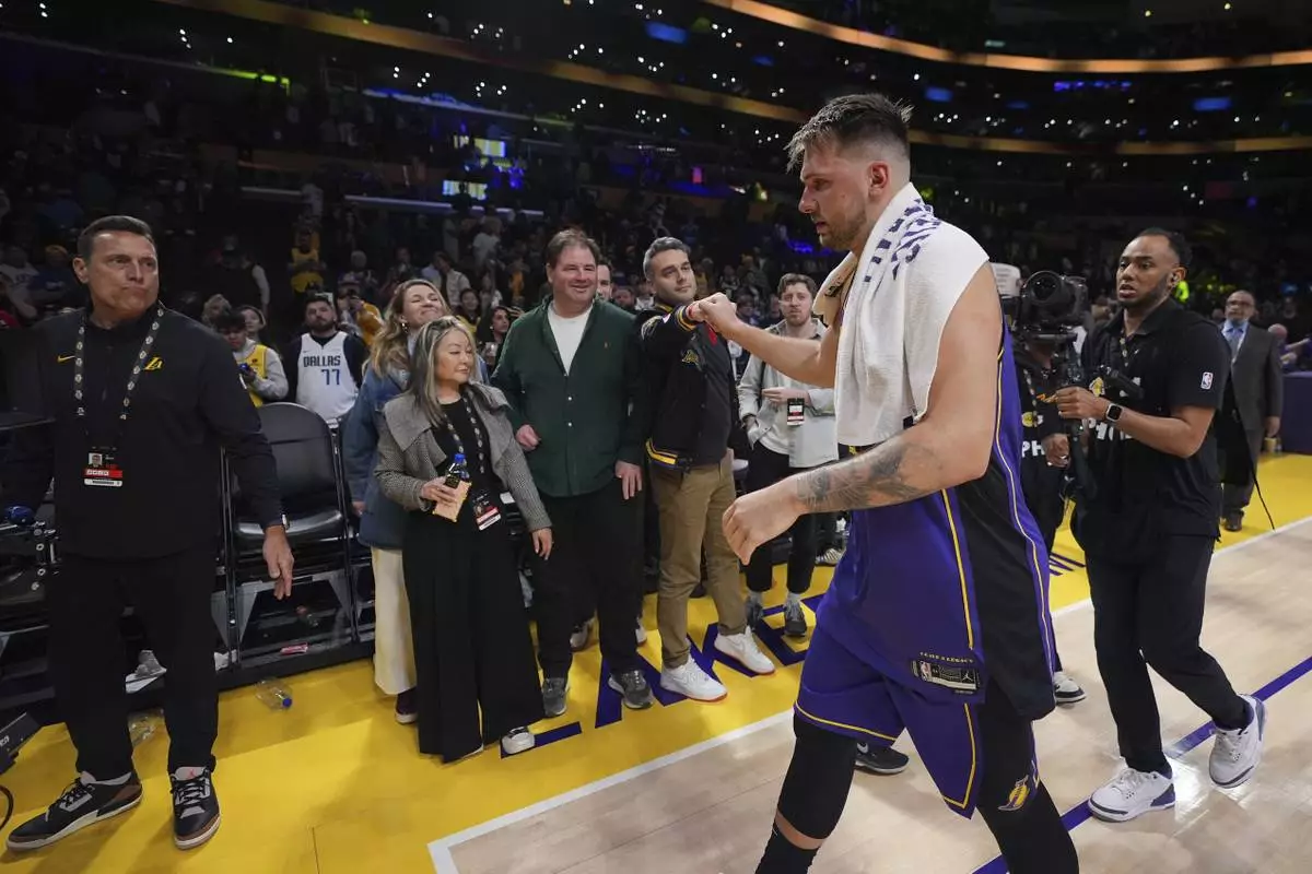 Los Angeles Lakers guard Luka Doncic, second from right, is greeted by a fan as he walks off the court after the team's victory over the Dallas Mavericks in an NBA basketball game Tuesday, Feb. 25, 2025, in Los Angeles. (AP Photo/Mark J. Terrill)