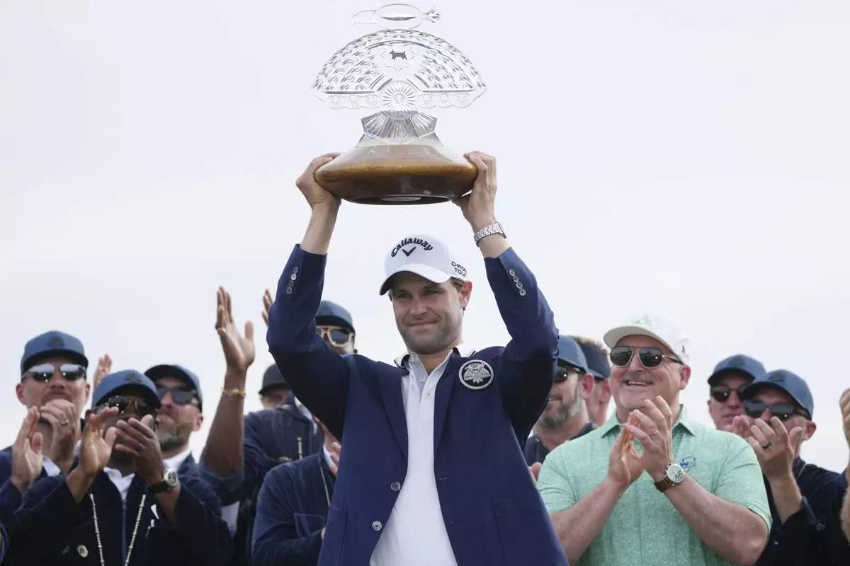 Thomas Detry, center, of Belgium, smiles as celebrates after his win at the Phoenix Open golf tournament at TPC Scottsdale while holding the winner's trophy and posing for photographers Sunday, Feb. 9, 2025, in Scottsdale, Ariz. (AP Photo/Ross D. Franklin)