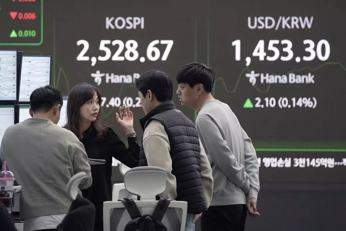 Currency traders work near a screen showing the Korea Composite Stock Price Index (KOSPI) and the foreign exchange rate between U.S. dollar and South Korean won, top right, at the foreign exchange dealing room of the KEB Hana Bank headquarters in Seoul, South Korea, Tuesday, Feb. 11, 2025. (AP Photo/Ahn Young-joon)