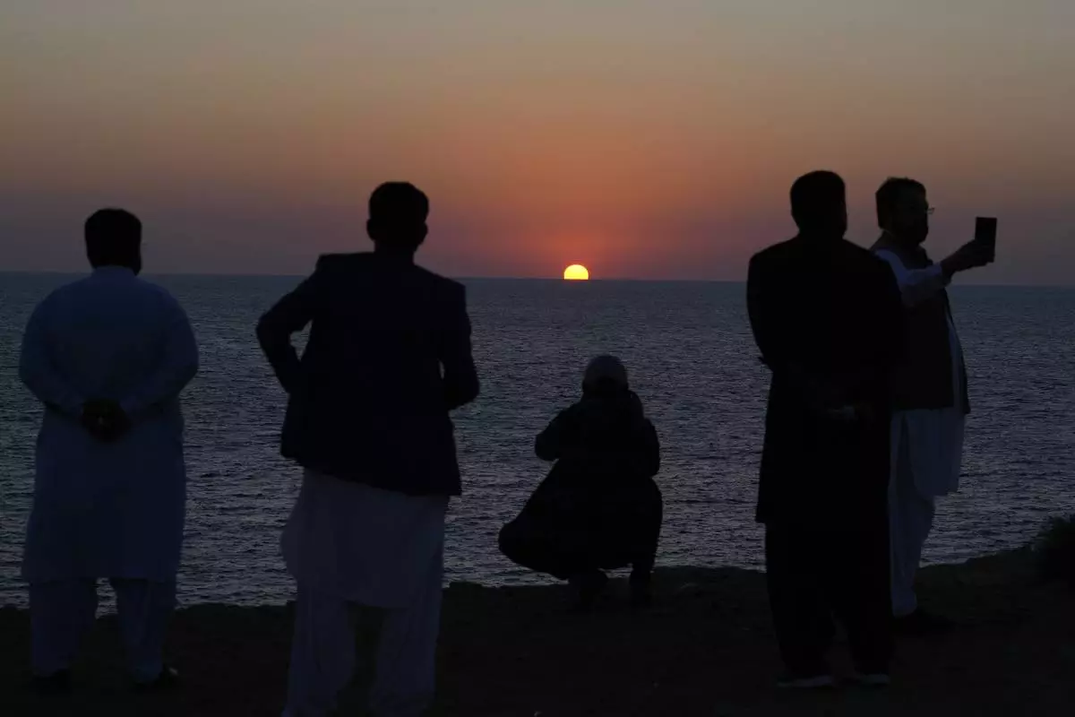 People take pictures as the sun sets along the beach in the coastal city of Gwadar, in the southwest Pakistani province of Balochistan, Jan. 14, 2025. (AP Photo/Anjum Naveed)