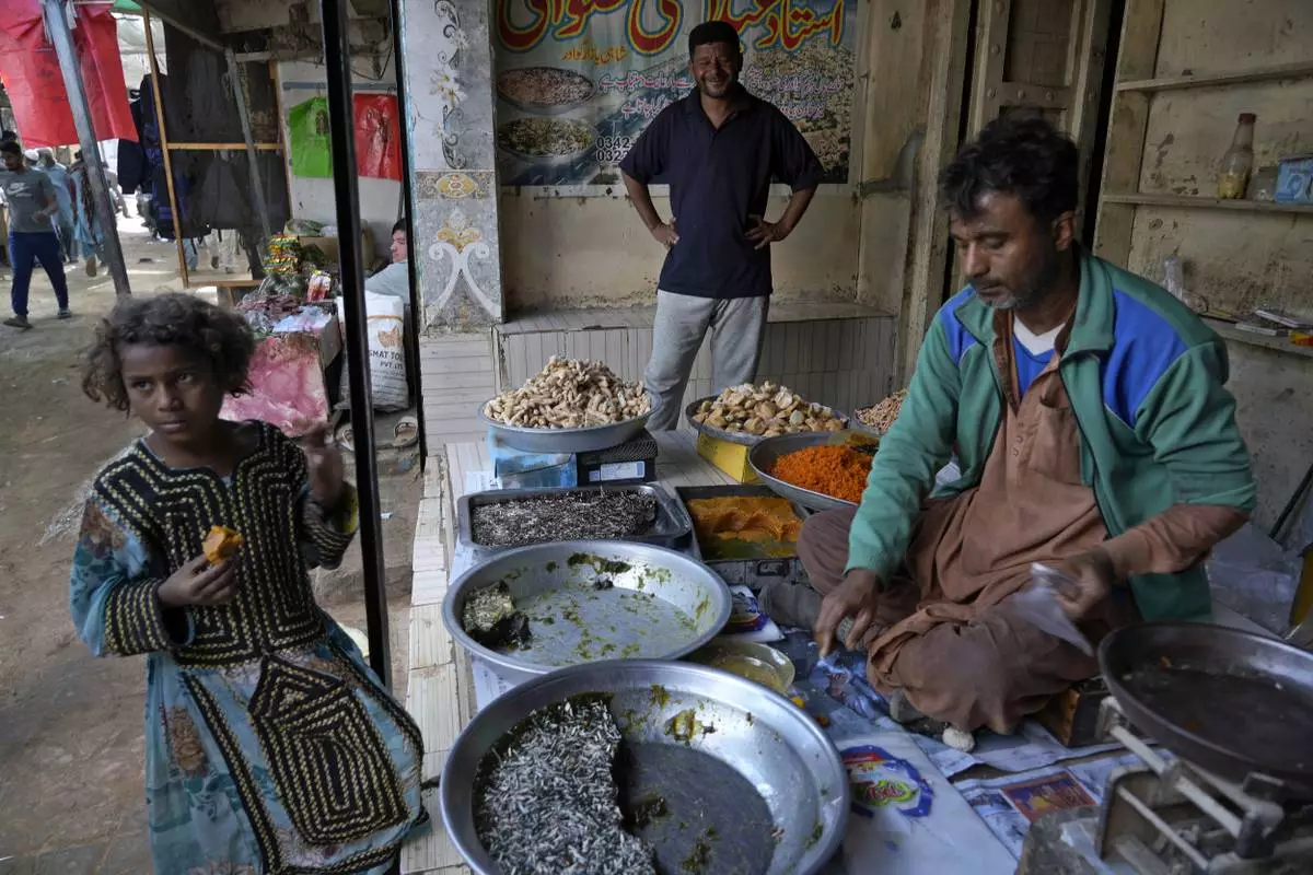 A girl buys traditional sweets from a shop at a market in the coastal city of Gwadar, in the southwest Pakistani province of Balochistan, Jan. 13, 2025. (AP Photo/Anjum Naveed)