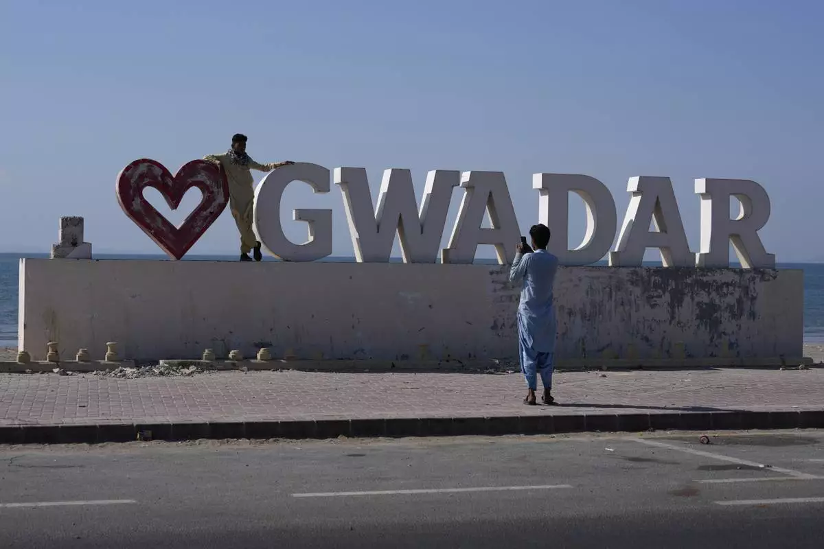 A boy takes pictures of his friend with a "Gwadar" sign at a newly constructed highway along the beach in the coastal city of Gwadar, in the southwest Pakistani province of Balochistan, Jan. 14, 2025. (AP Photo/Anjum Naveed)