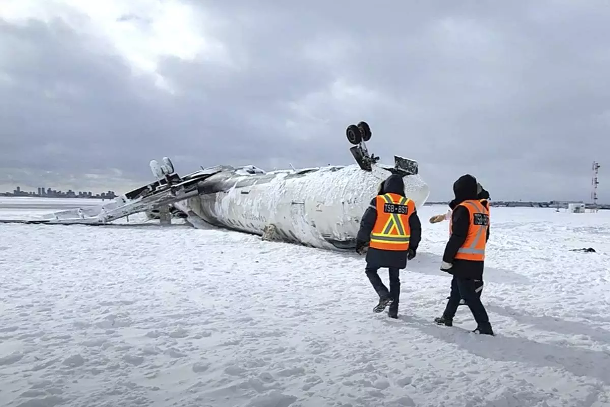 CORRECTS SOURCE TO TRANSPORTATION SAFETY BOARD OF CANADA INSTEAD OF NATIONAL TRANSPORTATION SAFETY BOARD - In this image provided by the Transportation Safety Board of Canada, investigators examine the wreckage of a Delta Air Lines jet, Wednesday, Feb. 19, 2025, that burst into flames and flipped upside down as it tried to land on Feb. 17, at Toronto Pearson International Airport in Mississauga, Ontario. (Transportation Safety Board of Canada via AP)