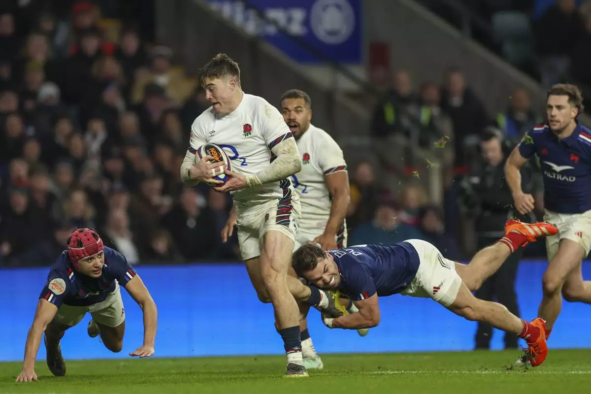 England's Tommy Freeman, center, breaks the tackle of France's Antoine Dupont to score a try during the Six Nations rugby union match between England and France at Twickenham in London, Saturday, Feb. 8, 2025. (AP Photo/Ian Walton)