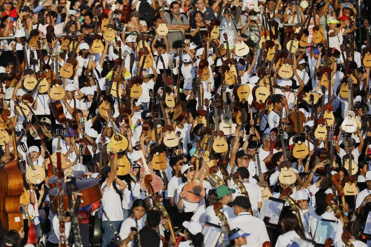 Youth raise their instruments during a concert celebrating the 50th anniversary of Venezuela's national system of children and youth orchestras in Caracas, Venezuela, Sunday, Feb. 23, 2025. (AP Photo/Cristian Hernandez)