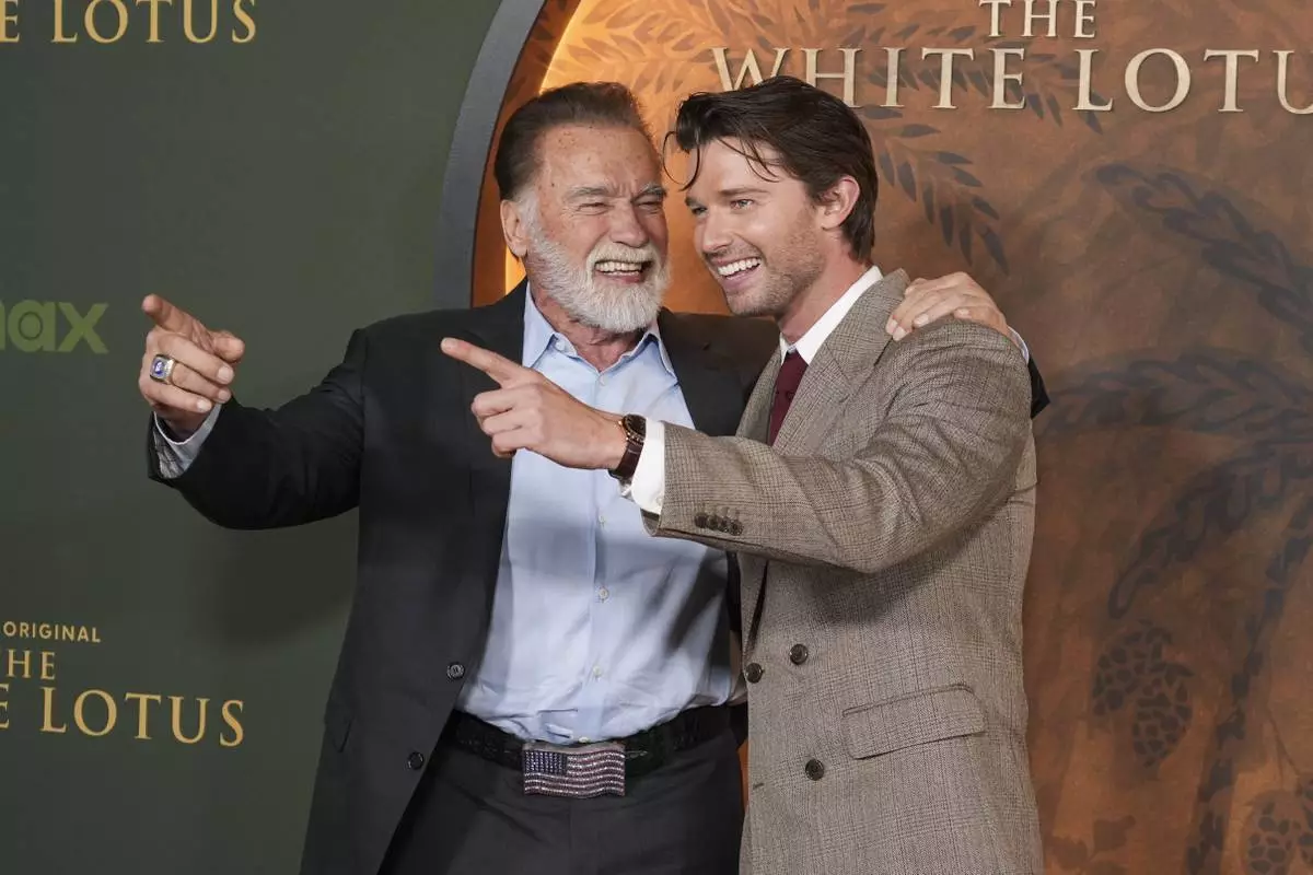 Arnold Schwarzenegger, left, and Patrick Schwarzenegger give the thumbs up at the season three premiere of "The White Lotus" on Monday, Feb. 10, 2025, at Paramount Theater in Los Angeles. (AP Photo/Chris Pizzello)