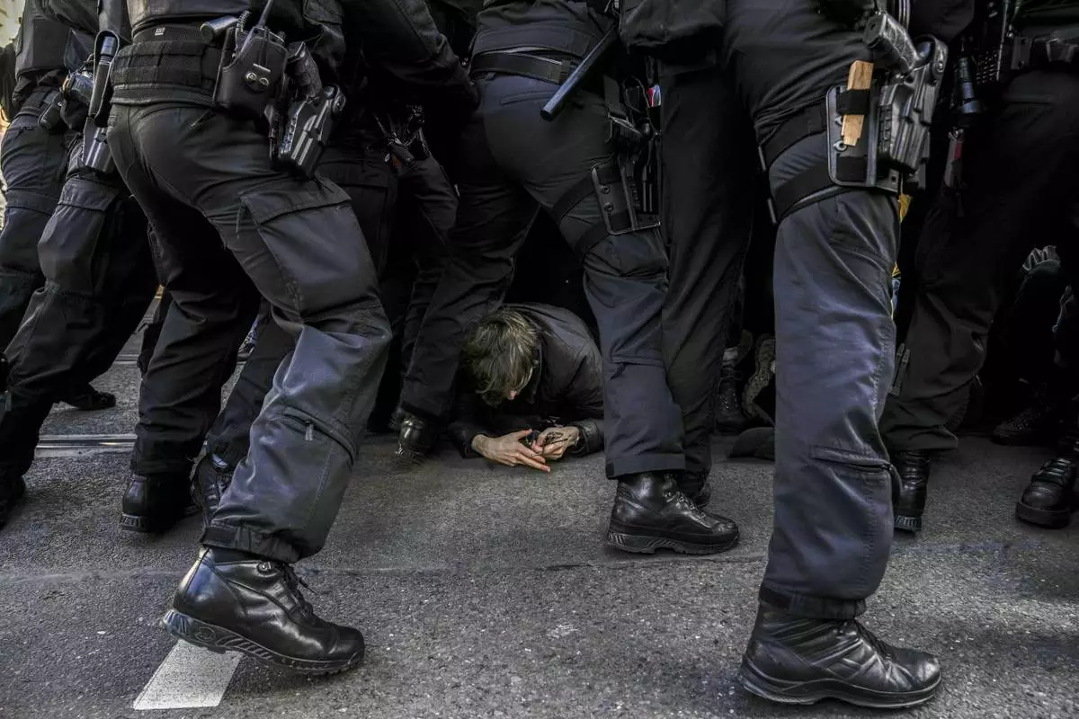Police officers remove anti-far-right protesters blocking the route of a far right demonstration, a day before the German election, in Berlin, Germany, Saturday, Feb. 22, 2025. (AP Photo/Ebrahim Noroozi)