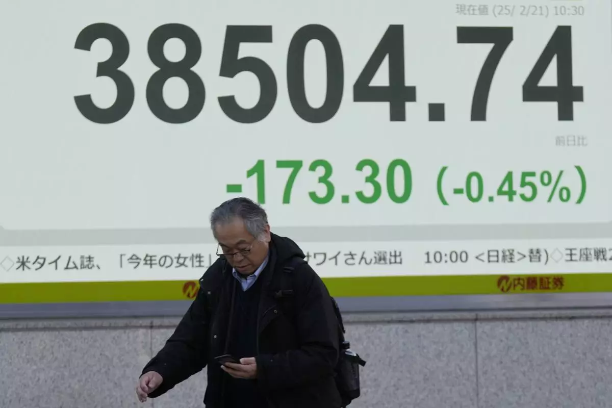 A person walks in front of an electronic stock board showing Japan's Nikkei index at a securities firm Friday, Feb. 21, 2025, in Tokyo. (AP Photo/Eugene Hoshiko)