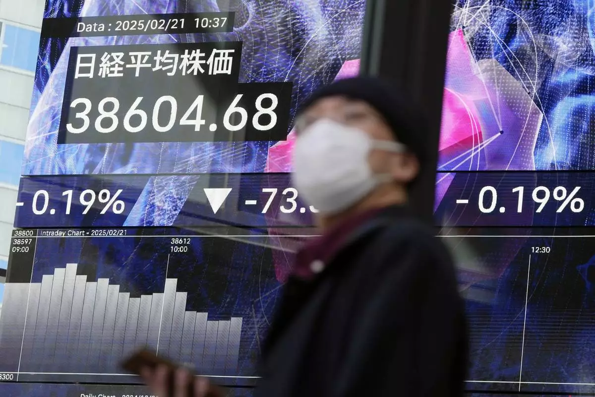 A person walks in front of an electronic stock board showing Japan's Nikkei index at a securities firm Friday, Feb. 21, 2025, in Tokyo. (AP Photo/Eugene Hoshiko)
