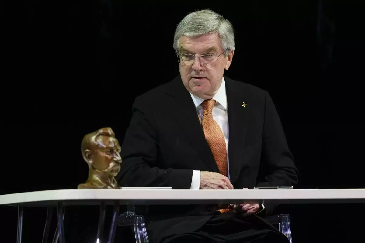 IOC President Thomas Bach looks at the sculpture of Pierre Decoubertin during the ceremony 'One Year To Go' for the 2026 Milano-Cortina Winter Olympics, at the Strehler Theatre, in Milan, Thursday, Feb. 6, 2025. (AP Photo/Luca Bruno)