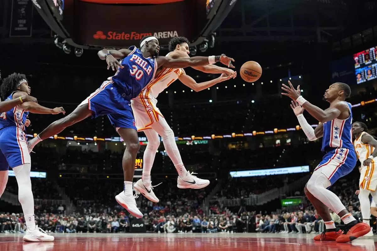 Atlanta Hawks forward Zaccharie Risacher (10) and Philadelphia 76ers center Adem Bona (30) vie for a rebound during the first half of an NBA basketball game, Monday, March 10, 2025, in Atlanta. (AP Photo/Mike Stewart)