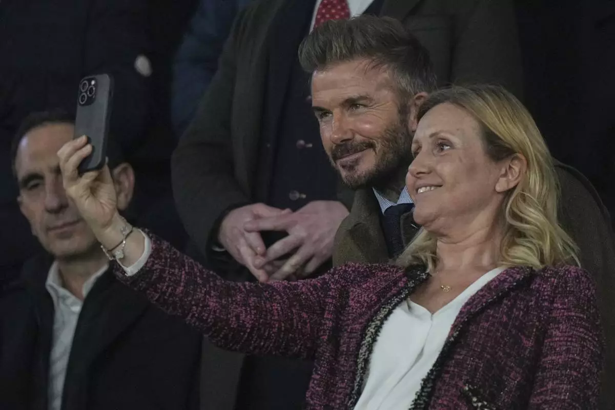 Former England soccer player David Beckham, center, poses for a photo with a spectator before the Champions League round of 16 first leg soccer match between Paris Saint-Germain and Liverpool at the Parc des Princes in Paris, Wednesday, March 5, 2025. (AP Photo/Aurelien Morissard)