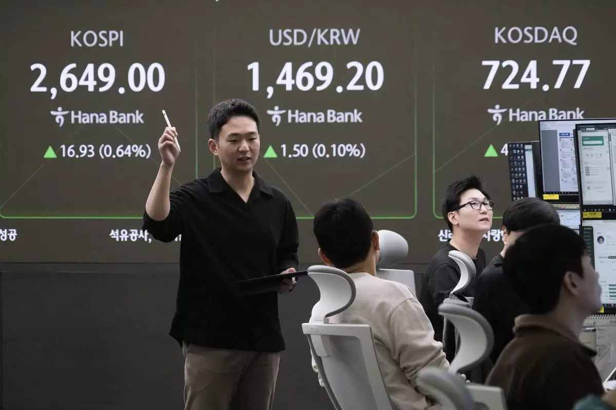Currency traders work near a screen showing the Korea Composite Stock Price Index (KOSPI), top left, and the foreign exchange rate between U.S. dollar and South Korean won, top center, at the foreign exchange dealing room of the KEB Hana Bank headquarters in Seoul, South Korea, Tuesday, March 25, 2025. (AP Photo/Ahn Young-joon)