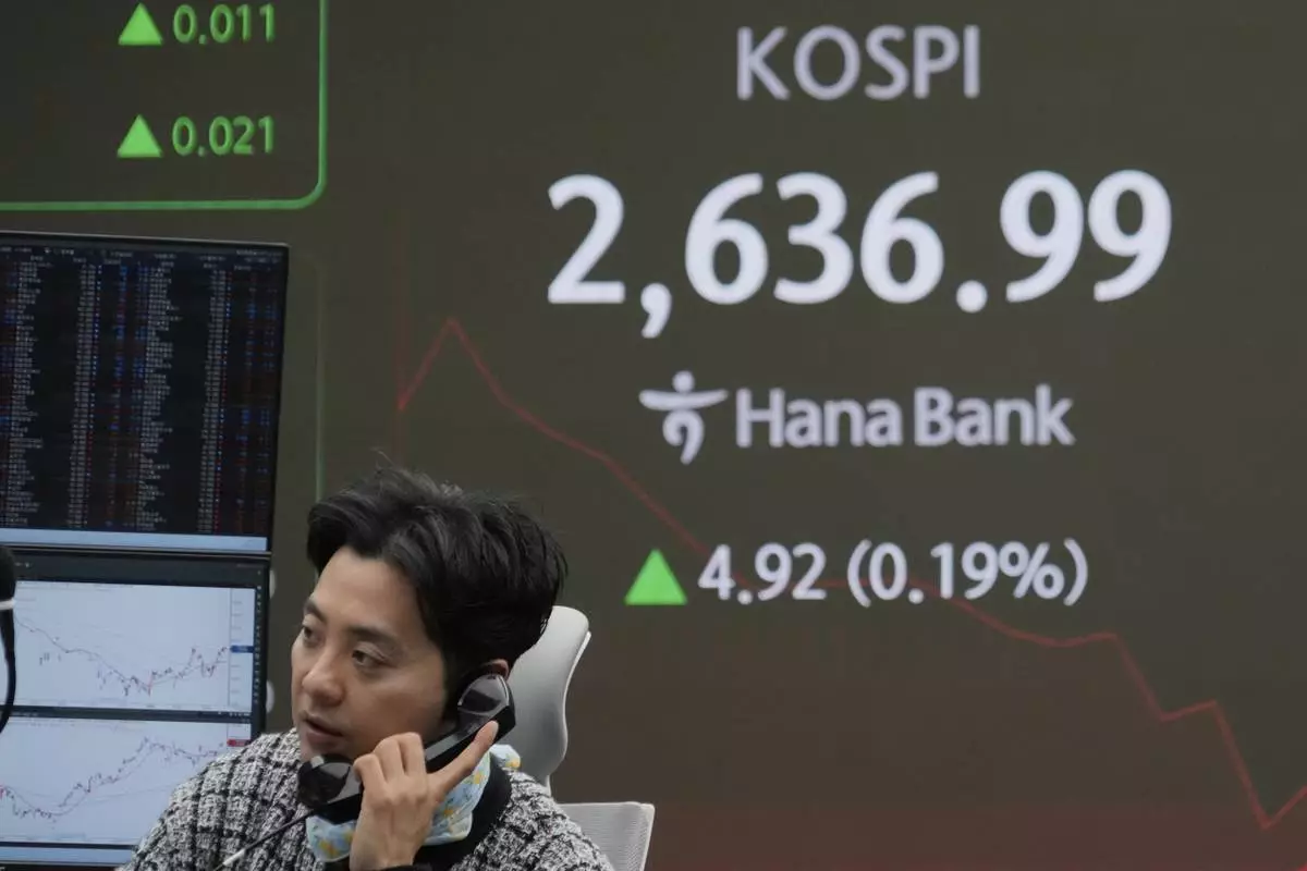 A currency trader talks on the phone near a screen showing the Korea Composite Stock Price Index (KOSPI) at the foreign exchange dealing room of the KEB Hana Bank headquarters in Seoul, South Korea, Tuesday, March 25, 2025. (AP Photo/Ahn Young-joon)