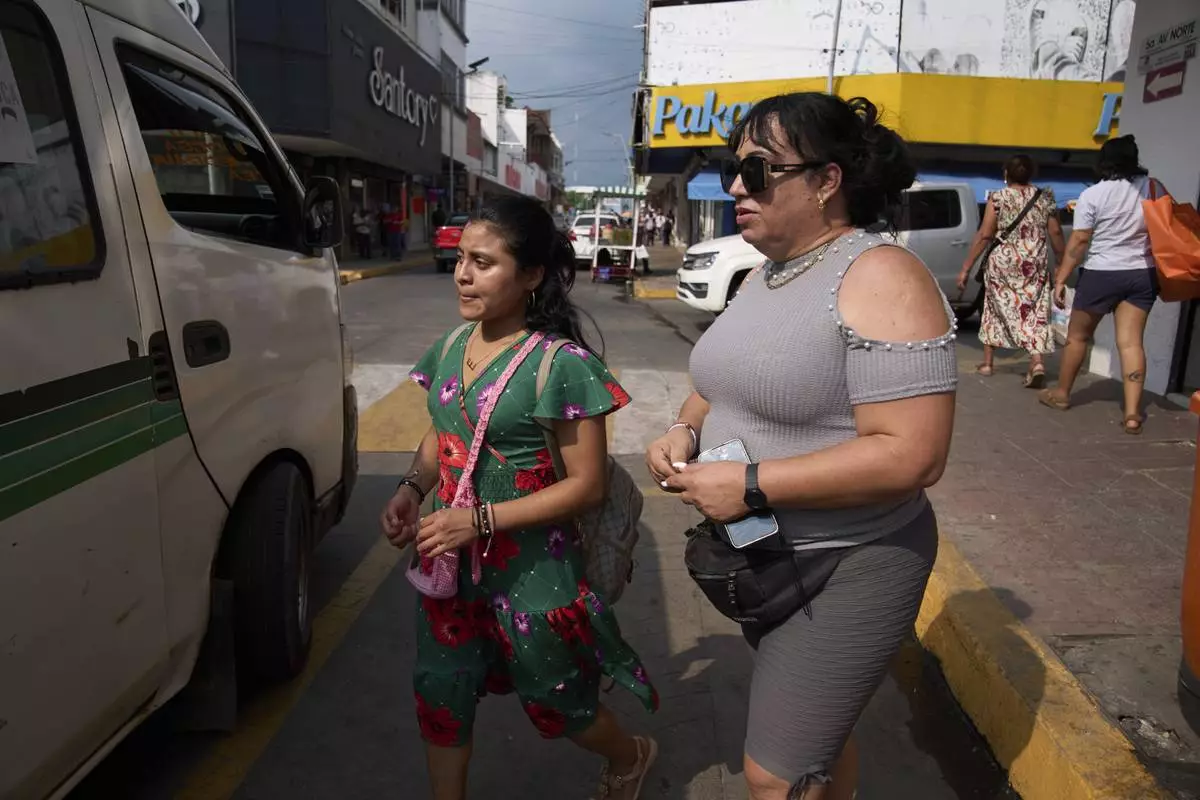 Transgender woman Ana Esquivel, right, who applied for asylum in Mexico, boards a bus in Tapachula, Chiapas state, Mexico, Tuesday, March 11, 2025. (AP Photo/Moises Castillo)