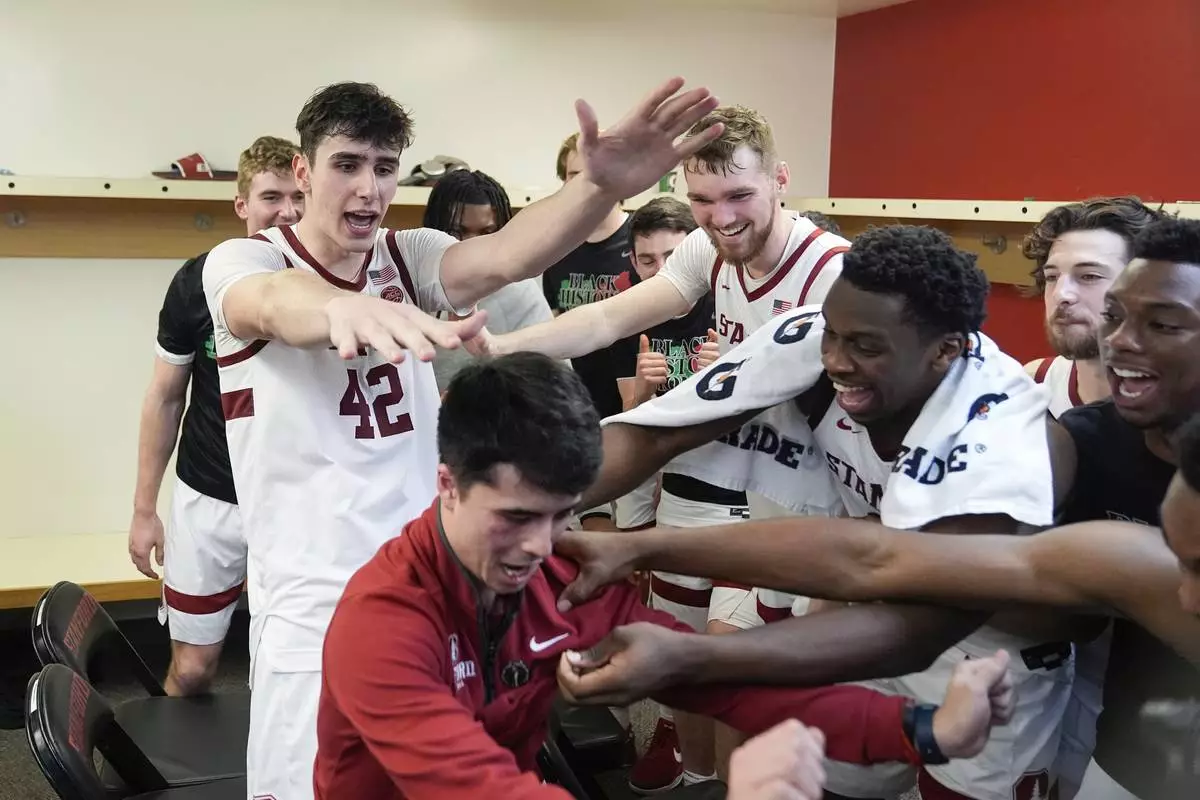 Stanford forward Maxime Raynaud (42) and celebrates with teammates and Alex Yano, director of basketball operations, inside the locker room after the team's victory over California in an NCAA college basketball game Saturday, Feb. 22, 2025, in Stanford, Calif. (AP Photo/Godofredo A. Vásquez)