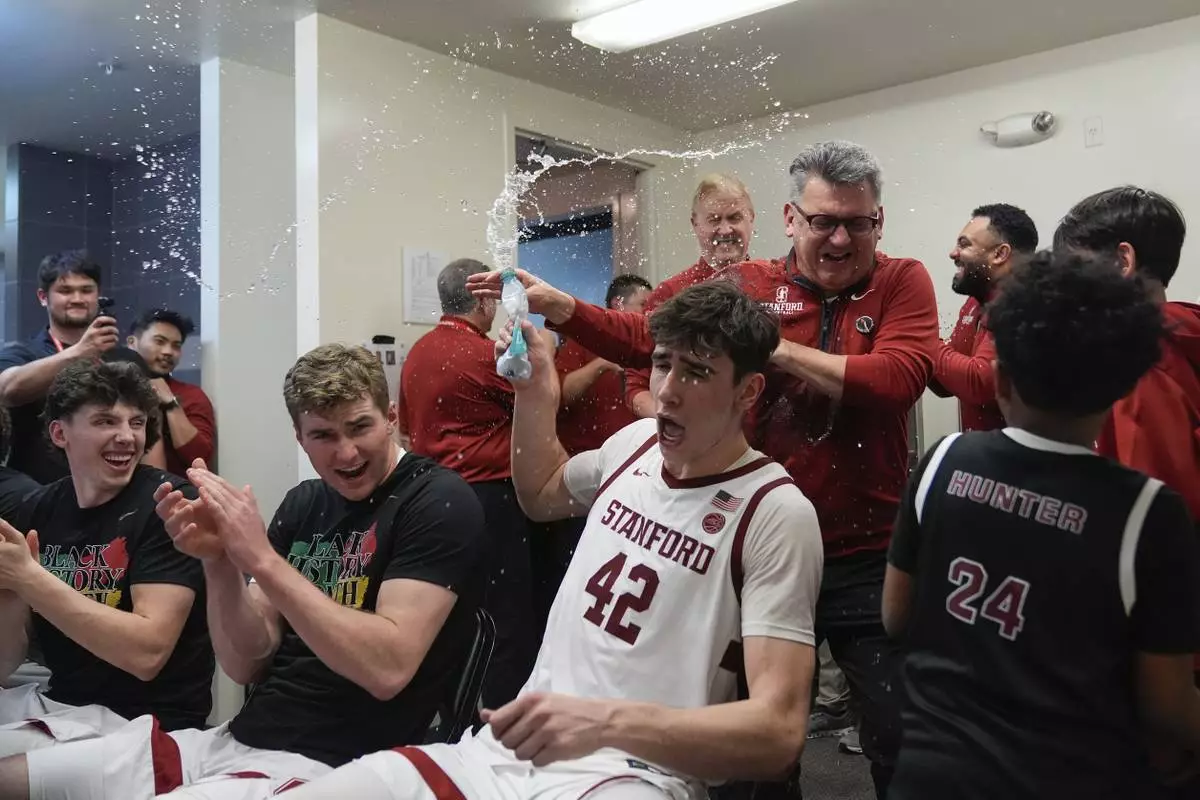 Stanford forward Maxime Raynaud (42) douses head coach Kyle Smith, wearing glasses, with water in the locker room after the team's victory over California in an NCAA college basketball game Saturday, Feb. 22, 2025, in Stanford, Calif. (AP Photo/Godofredo A. Vásquez)