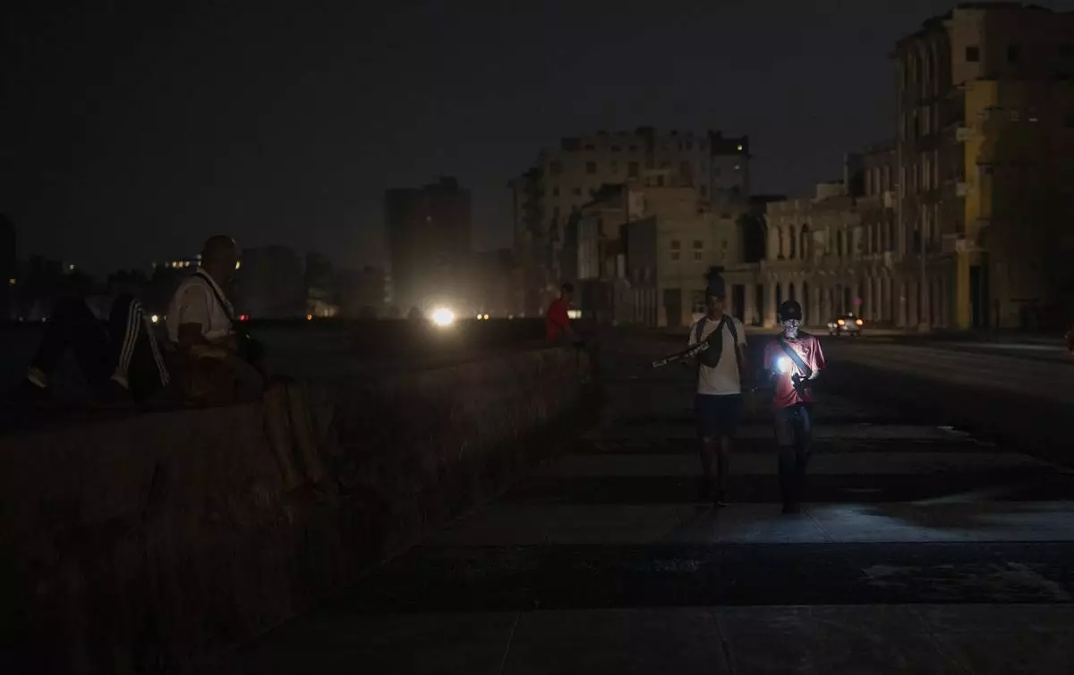 Residents walk on a street during a general blackout in Havana, Cuba, Friday, March 14, 2025. (AP Photo/Ramon Espinosa)
