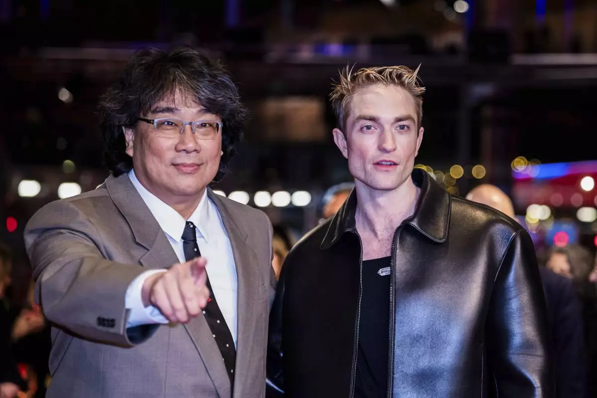 Actor Robert Pattinson, right, and Bong Joon Ho, left, pose for the photographers as they arrive for the screening of the film 'Mickey 17' at the International Film Festival, Berlinale, in Berlin, Saturday, Feb. 15, 2025. (Christoph Soeder/dpa via AP)