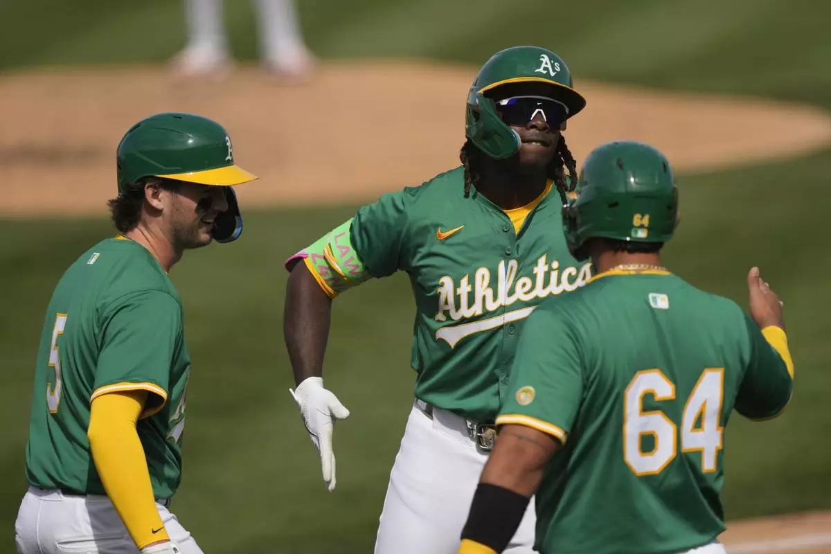 Athletics' Lawrence Butler, center, celebrates after his three-run home run with Jacob Wilson (5) and Jhonny Pereda (64) during the second inning of a spring training baseball game against the Cincinnati Reds, Friday, Feb. 28, 2025, in Mesa, Ariz. (AP Photo/Carolyn Kaster)