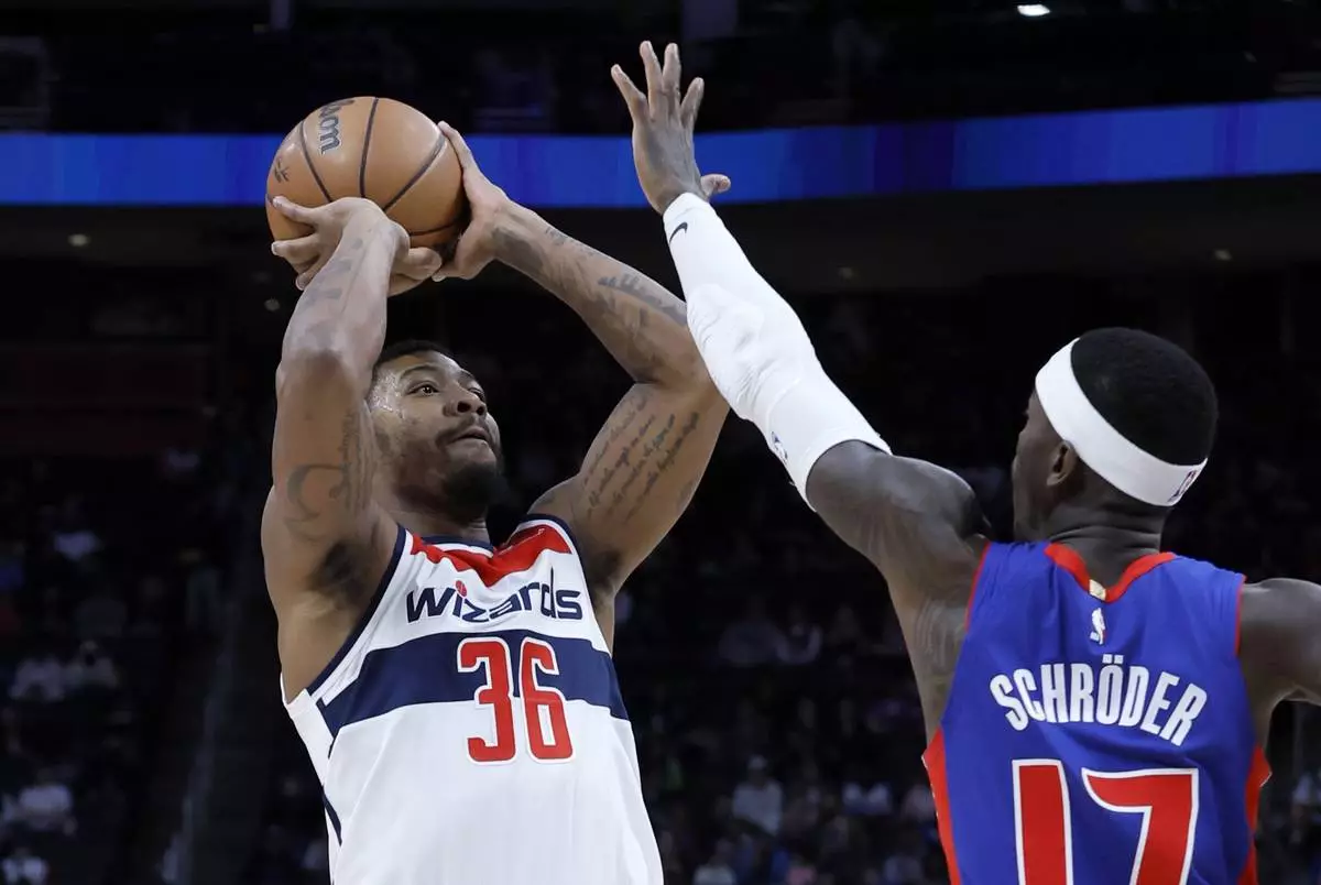 Washington Wizards guard Marcus Smart (36) takes a shot against Detroit Pistons guard Dennis Schroder (17) during the first half of an NBA basketball game Tuesday, March 11, 2025, in Detroit. (AP Photo/Duane Burleson)