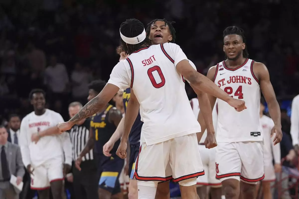 St. John's's Aaron Scott (0) celebrates with Simeon Wilcher and Zuby Ejiofor (24) during the second half of an NCAA college basketball game against the Marquette in the semifinals of the Big East tournament Friday, March 14, 2025, in New York. (AP Photo/Frank Franklin II)