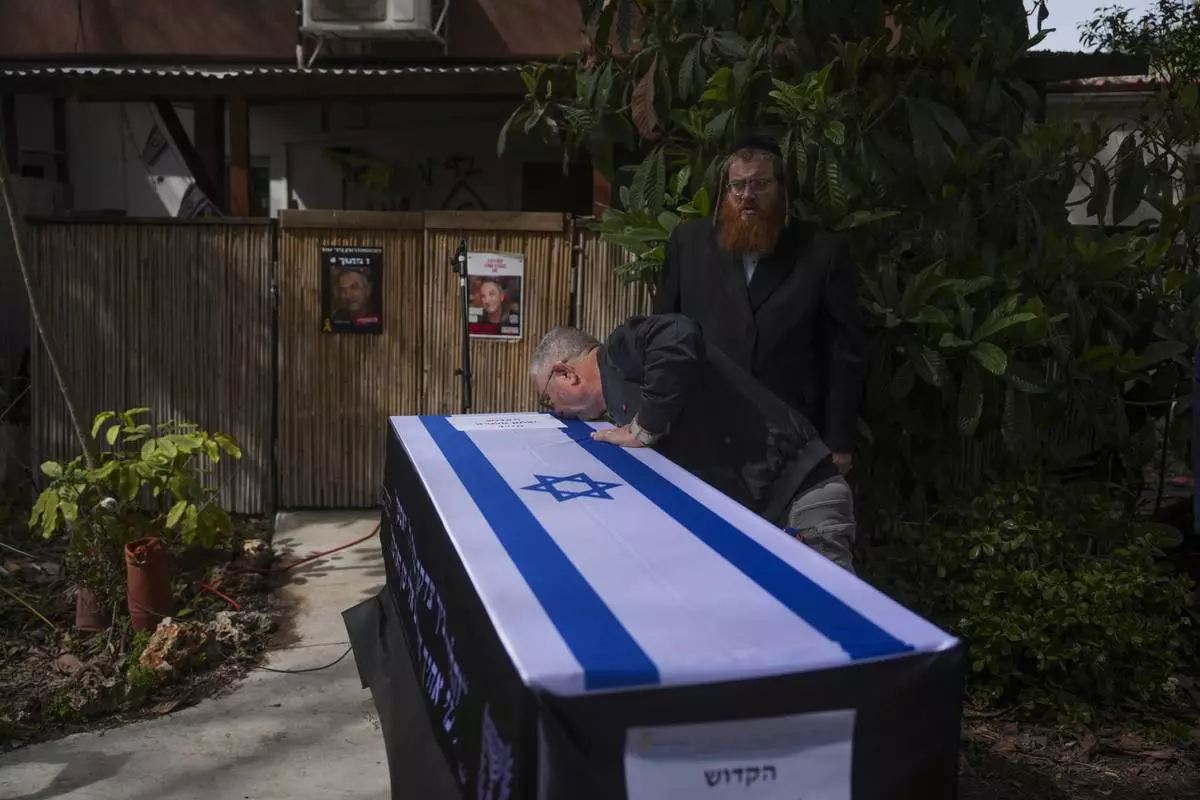 Danny Elgarat, kisses coffin of his brother, Itzhak Elgarat, a slain hostage who was held captive by Hamas in Gaza, during his funeral procession in Kibbutz Nir Oz, Israel, on Monday, March 3, 2025. (AP Photo/Ohad Zwigenberg)