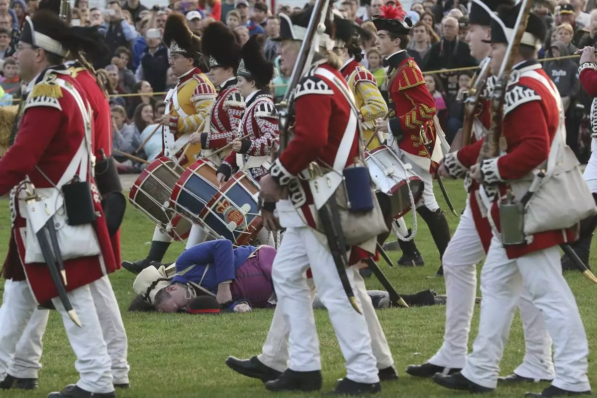 FILE - The British march off to Concord, leaving Lexington militia dead or dying on Lexington Green during a reenactment of the Battle of Lexington, Monday, April 17, 2017, in Lexington, Mass. (Ann Ringwood/The Metro West Daily News via AP,File)