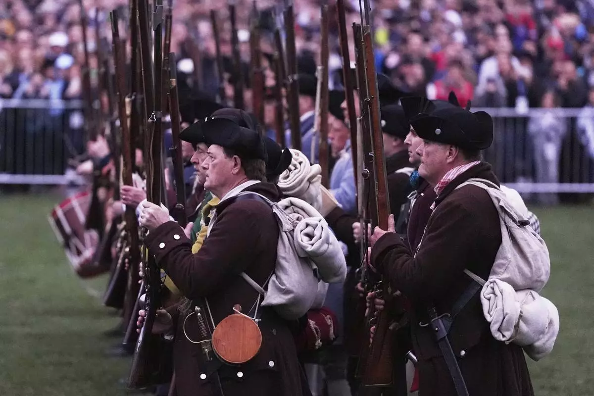 New England colonial militia, also known as a Minuteman, stand in line while facing the British Regulars during a reenactment celebration of the 250th anniversary of the Battle of Lexington and start of the American Revolution, Saturday, April 19, 2025, in Lexington, Mass. (AP Photo/Charles Krupa)